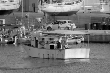 İtalya, Sicilya, Marina di Ragusa (Ragusa Eyaleti); limandaki ahşap bir balıkçı teknesinde balıkçı. 