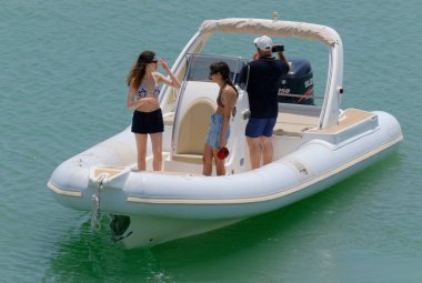 İtalya, Sicilya, Akdeniz, Marina di Ragusa (Ragusa Eyaleti); 1 Temmuz 2023, limandaki kauçuk bir teknede insanlar - EDITORIAL