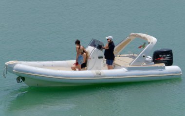 İtalya, Sicilya, Akdeniz, Marina di Ragusa (Ragusa Eyaleti); 1 Temmuz 2023, limandaki kauçuk bir teknede insanlar - EDITORIAL