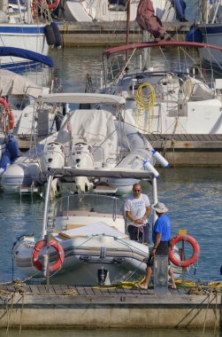 İtalya, Sicilya, Akdeniz, Marina di Ragusa (Ragusa Eyaleti); 5 Temmuz 2023, limandaki kauçuk bir teknede adam - EDITORIAL