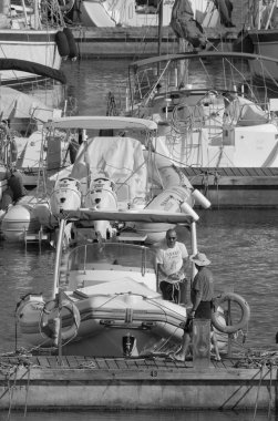 İtalya, Sicilya, Akdeniz, Marina di Ragusa (Ragusa Eyaleti); 5 Temmuz 2023, limandaki kauçuk bir teknede adam - EDITORIAL