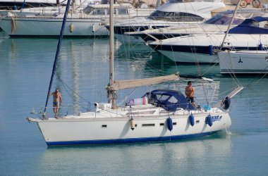 İtalya, Sicilya, Akdeniz, Marina di Ragusa (Ragusa Eyaleti); 7 Temmuz 2023, limandaki bir yelkenli ve lüks yatlarda erkekler - EDITORIAL