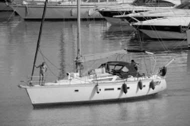 İtalya, Sicilya, Akdeniz, Marina di Ragusa (Ragusa Eyaleti); 7 Temmuz 2023, limandaki bir yelkenli ve lüks yatlarda erkekler - EDITORIAL