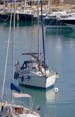 İtalya, Sicilya, Akdeniz, Marina di Ragusa (Ragusa Eyaleti); 7 Temmuz 2023, limandaki bir yelkenli ve lüks yatlarda erkekler - EDITORIAL