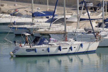 İtalya, Sicilya, Akdeniz, Marina di Ragusa (Ragusa Eyaleti); 7 Temmuz 2023, limandaki bir yelkenli ve lüks yatlarda erkekler - EDITORIAL