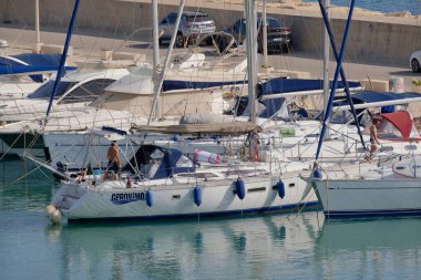 İtalya, Sicilya, Akdeniz, Marina di Ragusa (Ragusa Eyaleti); 7 Temmuz 2023, limandaki bir yelkenli ve lüks yatlarda erkekler - EDITORIAL