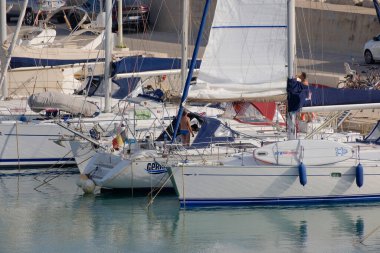 İtalya, Sicilya, Akdeniz, Marina di Ragusa (Ragusa ili); 7 Temmuz 2023, limanda yelkenli tekneleri ve lüks yatlarda erkekler - EDITORIAL