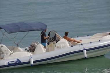 İtalya, Sicilya, Akdeniz, Marina di Ragusa (Ragusa ili); 8 Temmuz 2023, limanda büyük bir kauçuk teknede çift - EDITORIAL