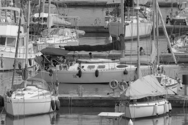 İtalya, Sicilya, Akdeniz, Marina di Ragusa (Ragusa ili); 9 Temmuz 2023, limandaki bir yelkenli teknesinde insanlar - EDITORIAL