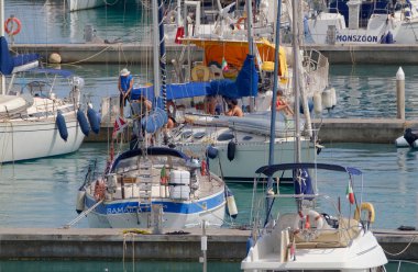 İtalya, Sicilya, Akdeniz, Marina di Ragusa (Ragusa ili); 9 Temmuz 2023, limandaki bir yelkenli teknesinde insanlar - EDITORIAL