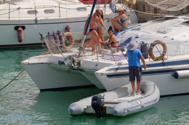 İtalya, Sicilya, Akdeniz, Marina di Ragusa (Ragusa ili); 9 Temmuz 2023, limandaki bir yelkenli teknesinde insanlar - EDITORIAL