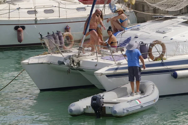 İtalya, Sicilya, Akdeniz, Marina di Ragusa (Ragusa ili); 9 Temmuz 2023, limandaki bir yelkenli teknesinde insanlar - EDITORIAL