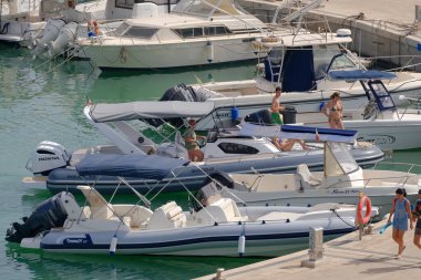 İtalya, Sicilya, Akdeniz, Marina di Ragusa (Ragusa Eyaleti); 9 Temmuz 2023, limandaki lastik bir teknede köpeği olan insanlar - EDITORIAL