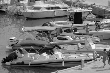 İtalya, Sicilya, Akdeniz, Marina di Ragusa (Ragusa Eyaleti); 9 Temmuz 2023, limandaki lastik bir teknede köpeği olan insanlar - EDITORIAL