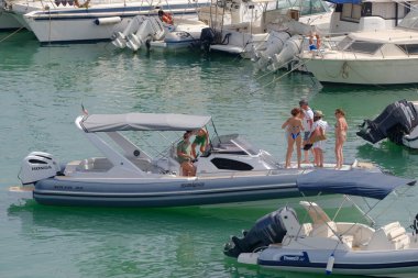 İtalya, Sicilya, Akdeniz, Marina di Ragusa (Ragusa Eyaleti); 9 Temmuz 2023, limandaki kauçuk bir teknede insanlar - EDITORIAL