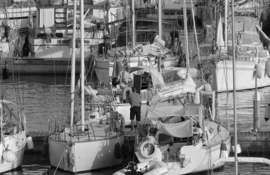 İtalya, Sicilya, Akdeniz, Marina di Ragusa (Ragusa Eyaleti); 20 Temmuz 2023, limandaki bir yelkenli teknesinde adam - EDITORIAL