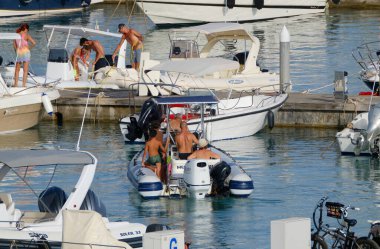 İtalya, Sicilya, Akdeniz, Marina di Ragusa (Ragusa ili); 29 Temmuz 2023, limanda insanlar ve motorlu tekneler - EDITORIAL