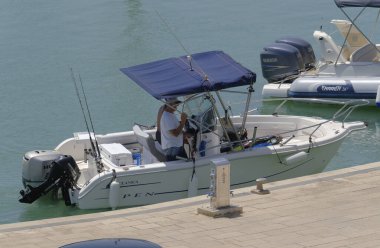 İtalya, Sicilya, Akdeniz, Marina di Ragusa (Ragusa Eyaleti); 30 Temmuz 2023, limandaki bir motorlu teknede balıkçı - EDITORIAL