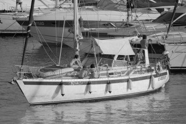 İtalya, Sicilya, Akdeniz, Marina di Ragusa (Ragusa Eyaleti); 11 Ağustos 2023, limandaki bir yelkenli teknesi ve lüks yatlarda yaşayan insanlar - EDITORIAL