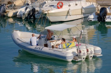 İtalya, Sicilya, Akdeniz, Marina di Ragusa (Ragusa ili); 13 Ağustos 2023, limandaki kauçuk bir teknede insanlar - EDITORIAL