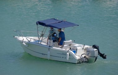 İtalya, Sicilya, Akdeniz, Marina di Ragusa (Ragusa ili); 14 Ağustos 2023, limandaki bir motorlu teknede erkekler - EDITORIAL