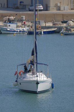 Italy, Sicily, Mediterranean Sea, Marina di Ragusa (Ragusa Province); couple on a sailing boat in the port 