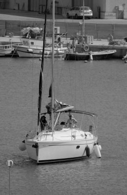 Italy, Sicily, Mediterranean Sea, Marina di Ragusa (Ragusa Province); couple on a sailing boat in the port 