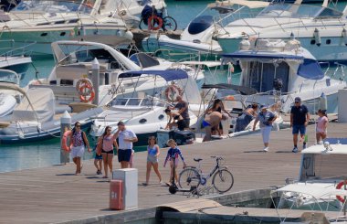 İtalya, Sicilya, Akdeniz, Marina di Ragusa (Ragusa ili); 15 Ağustos 2023, limandaki insanlar, motorlu tekneler ve lüks yatlar - EDITORIAL