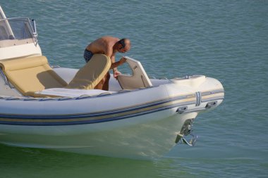 İtalya, Sicilya, Akdeniz, Marina di Ragusa (Ragusa ili); 18 Ağustos 2023, limandaki kauçuk bir teknede adam - EDITORIAL