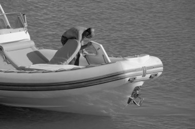 İtalya, Sicilya, Akdeniz, Marina di Ragusa (Ragusa ili); 18 Ağustos 2023, limandaki kauçuk bir teknede adam - EDITORIAL