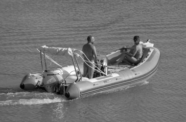 İtalya, Sicilya, Akdeniz, Marina di Ragusa (Ragusa ili); 19 Ağustos 2023, limanda kauçuk bir tekne ve lüks yatlarda bir çift - EDITORIAL