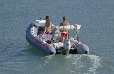 İtalya, Sicilya, Akdeniz, Marina di Ragusa (Ragusa ili); 19 Ağustos 2023, limanda kauçuk bir tekne ve lüks yatlarda bir çift - EDITORIAL