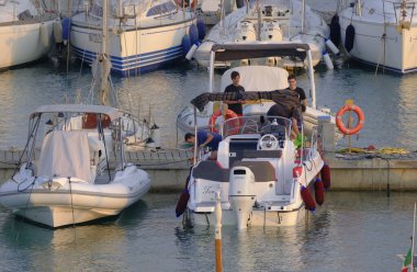 İtalya, Sicilya, Akdeniz, Marina di Ragusa (Ragusa Eyaleti); 22 Ağustos 2023, gün batımında limanda halk, motorlu tekne ve lüks yatlar - EDITORIAL