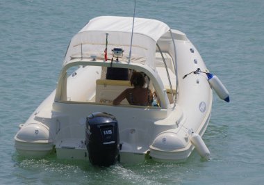 İtalya, Sicilya, Akdeniz, Marina di Ragusa (Ragusa ili); 26 Ağustos 2023, limanda kauçuk bir tekne ve lüks yatlarda bir çift - EDITORIAL