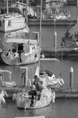 İtalya, Sicilya, Akdeniz, Marina di Ragusa (Ragusa ili); 26 Ağustos 2023, limanda bir yelkenli ve lüks yatlarda erkekler - EDITORIAL