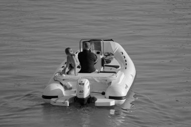 İtalya, Sicilya, Akdeniz, Marina di Ragusa (Ragusa ili); 27 Ağustos 2023, limanda kauçuk bir tekne ve lüks yatlarda bir çift - EDITORIAL