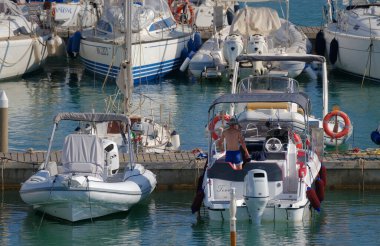 İtalya, Sicilya, Akdeniz, Marina di Ragusa (Ragusa Eyaleti); 1 Eylül 2023, limanda bir motorlu tekne ve lüks yatlarda adam - EDITORIAL