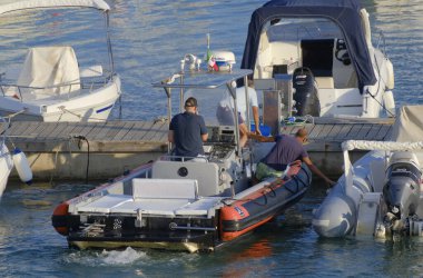 İtalya, Sicilya, Akdeniz, Marina di Ragusa (Ragusa Eyaleti); 2 Eylül 2023, limandaki kauçuk bir teknede erkekler - EDITORIAL