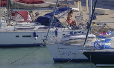 İtalya, Sicilya, Akdeniz, Marina di Ragusa (Ragusa Eyaleti); 14 Eylül 2023, limandaki bir yelkenli ve lüks yatlarda erkekler - EDITORIAL