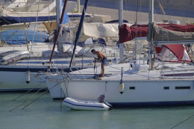 İtalya, Sicilya, Akdeniz, Marina di Ragusa (Ragusa Eyaleti); 14 Eylül 2023, limandaki bir yelkenli teknesinde adam - EDITORIAL