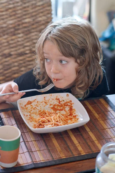Italy, Sicily, Marina di Ragusa (Ragusa Province); 7 years old male child eating pasta with tomato sauce in a dining room