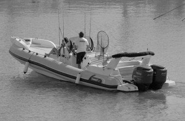 İtalya, Sicilya, Akdeniz, Marina di Ragusa (Ragusa ili); 7 Ekim 2023, limanda büyük bir kauçuk teknede çift - EDITORIAL