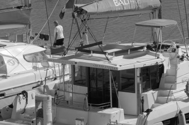 İtalya, Sicilya, Akdeniz, Marina di Ragusa (Ragusa Eyaleti); 29 Ekim 2023, limandaki bir katamaran yelkenli teknesinde adam - EDITORIAL