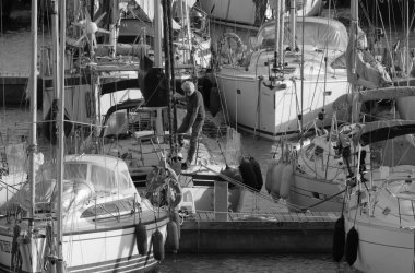 İtalya, Sicilya, Akdeniz, Marina di Ragusa (Ragusa Eyaleti); 31 Ekim 2023, limandaki bir yelkenli teknesinde adam - EDITORIAL