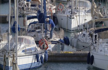 İtalya, Sicilya, Akdeniz, Marina di Ragusa (Ragusa Eyaleti); 31 Ekim 2023, limandaki bir yelkenli teknesinde adam - EDITORIAL