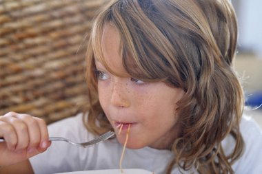 İtalya, Sicilya; 7 yaşında erkek çocuk domates soslu spagetti yiyor.