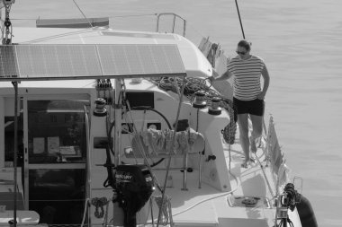 İtalya, Sicilya, Akdeniz, Marina di Ragusa (Ragusa Eyaleti); 8 Kasım 2023, limandaki katamaran yelkenli teknesinde bir kadın - EDITORIAL