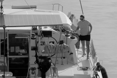 İtalya, Sicilya, Akdeniz, Marina di Ragusa (Ragusa Eyaleti); 8 Kasım 2023, limandaki katamaran yelkenli teknesinde bir kadın - EDITORIAL