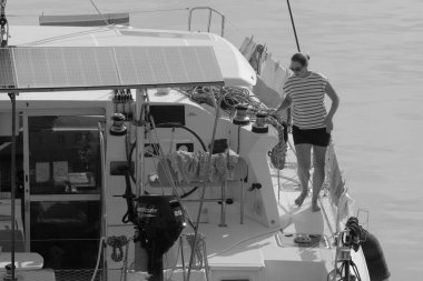 İtalya, Sicilya, Akdeniz, Marina di Ragusa (Ragusa Eyaleti); 8 Kasım 2023, limandaki katamaran yelkenli teknesinde bir kadın - EDITORIAL