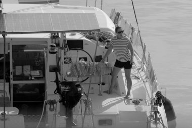 İtalya, Sicilya, Akdeniz, Marina di Ragusa (Ragusa Eyaleti); 8 Kasım 2023, limandaki katamaran yelkenli teknesinde bir kadın - EDITORIAL